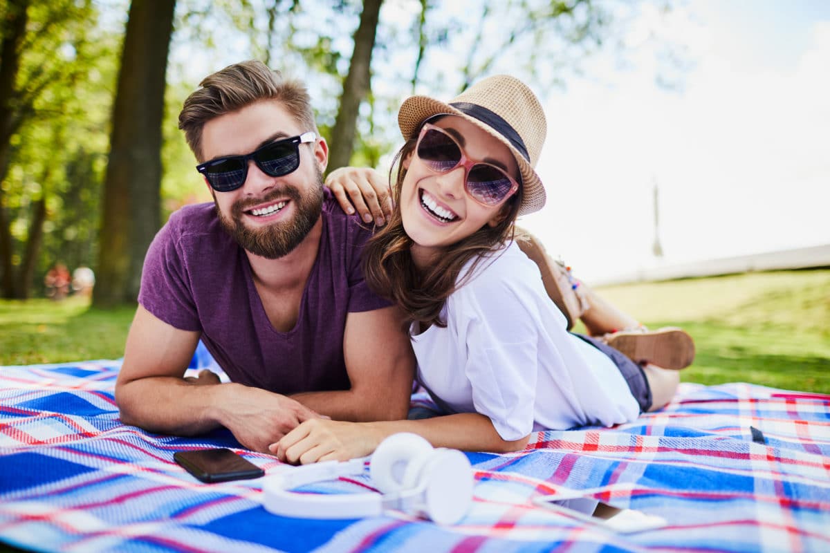 Couple smiles on a picnic blanket